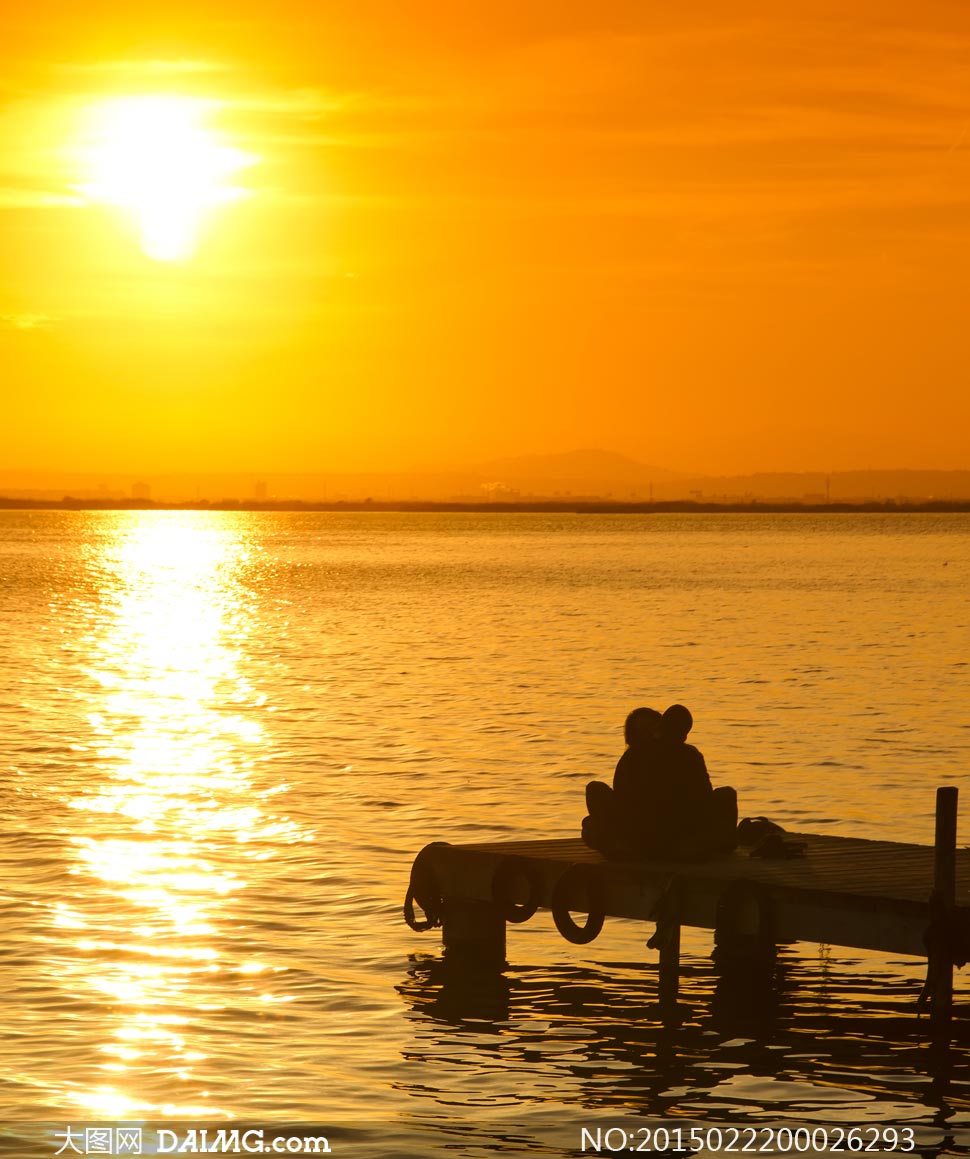 夕阳下在海边拥抱的情人摄影图片