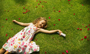 惬意地躺在草坪上的小女孩高清图片