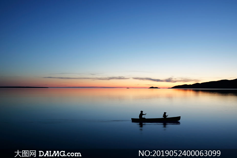 夕阳下在湖中滑行的小舟摄影图片
