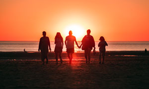 夕阳下的海边一家人剪影摄影图片