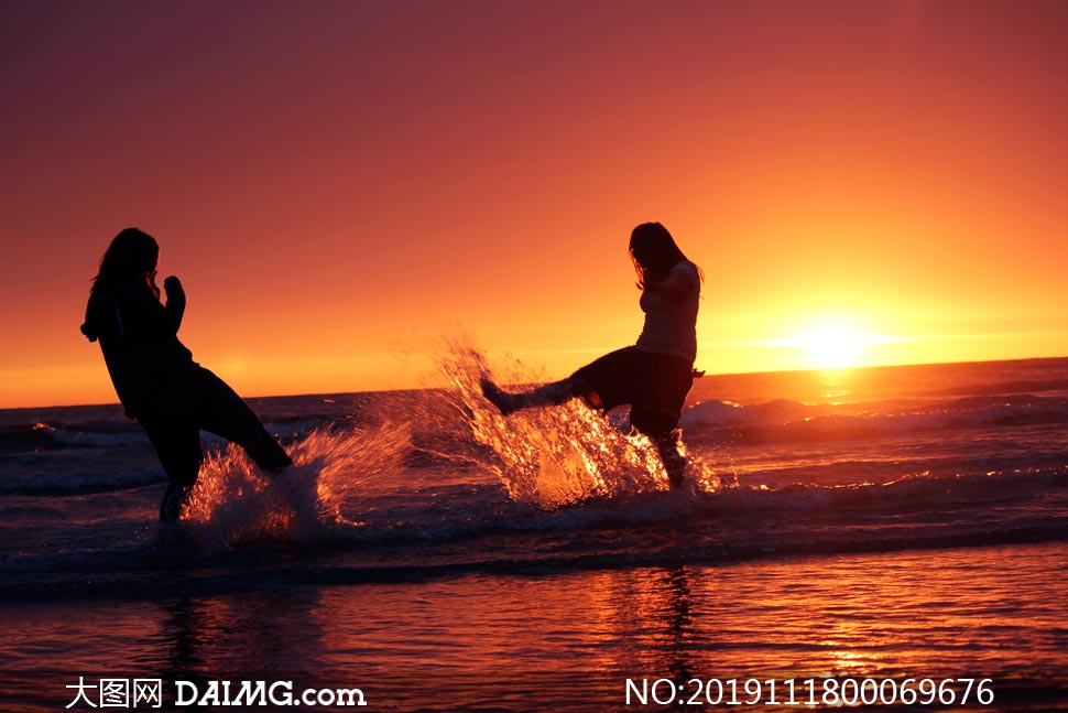 夕陽下在海邊戲水的美女攝影圖片