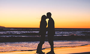 黄昏下海边的情侣接吻剪影摄影图片