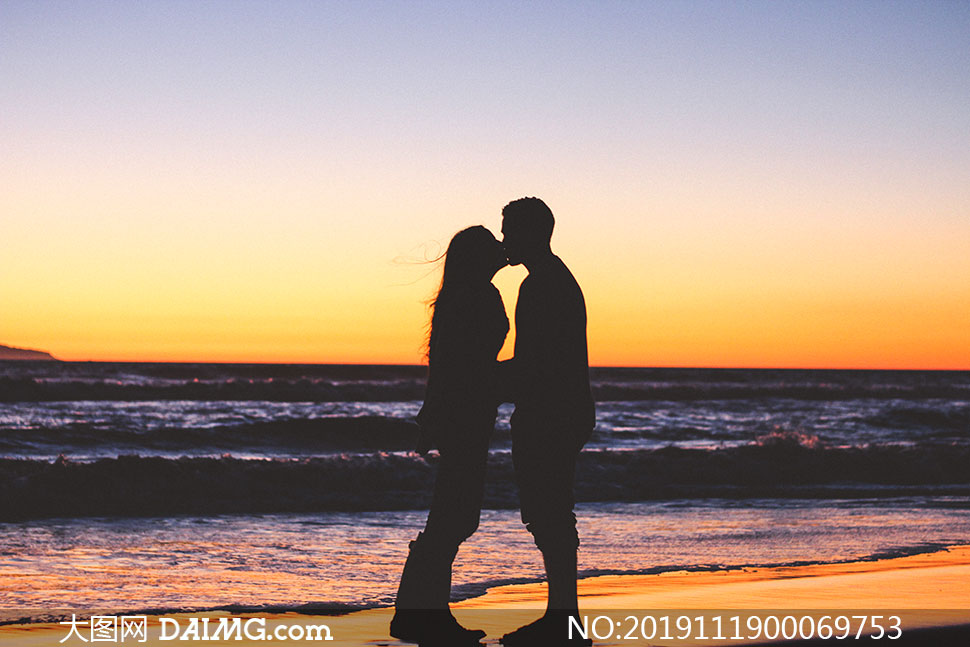 黄昏下海边的情侣接吻剪影摄影图片
