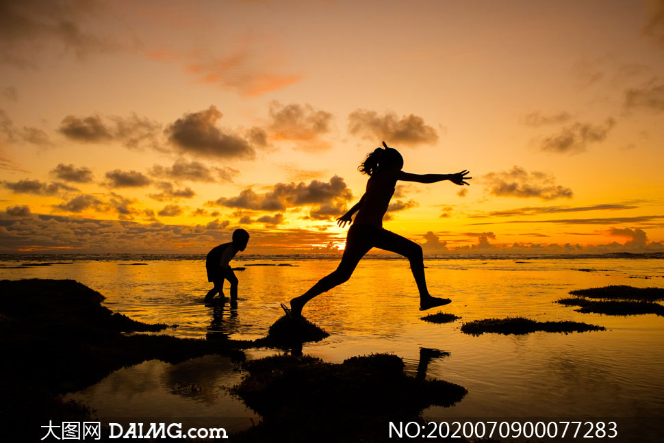 夕阳下海边玩耍的母子剪影摄影图片