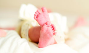 床上伸出的新生兒腳丫攝影圖片