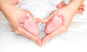心形手勢中的新生兒腳丫攝影圖片