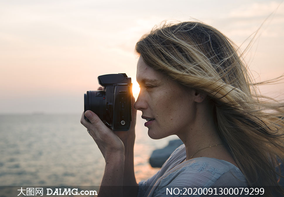 在海边拍照的美女摄影师摄影图片