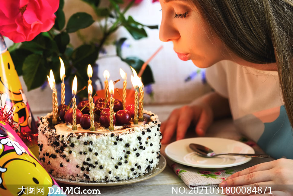 正在吹生日蛋糕蜡烛的美女摄影图片