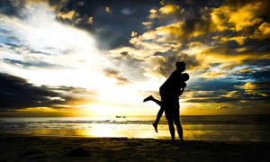 傍晚下海边拥抱的情侣剪影摄影图片