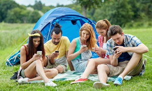 一群在草地上看手機的游客攝影圖片