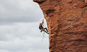 陡峭崖壁上的攀岩人物摄影高清图片
