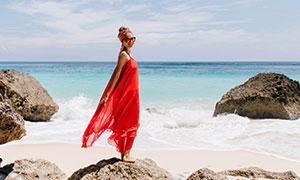 海边站在礁石上的红裙美女高清图片