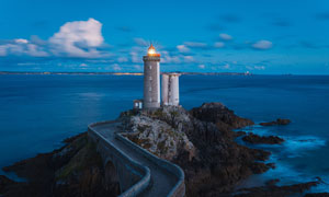 海邊亮起燈的燈塔攝影圖片