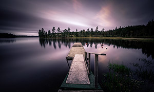 黃昏時湖畔棧橋與樹林攝影高清圖片