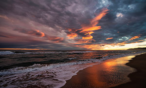 霞光映衬下的海滩波浪摄影高清图片