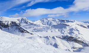 冬季蓝天白云下的雪山摄影图片