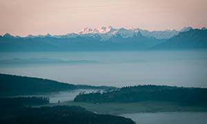 雪山與霧氣彌漫籠罩的湖泊攝影圖片